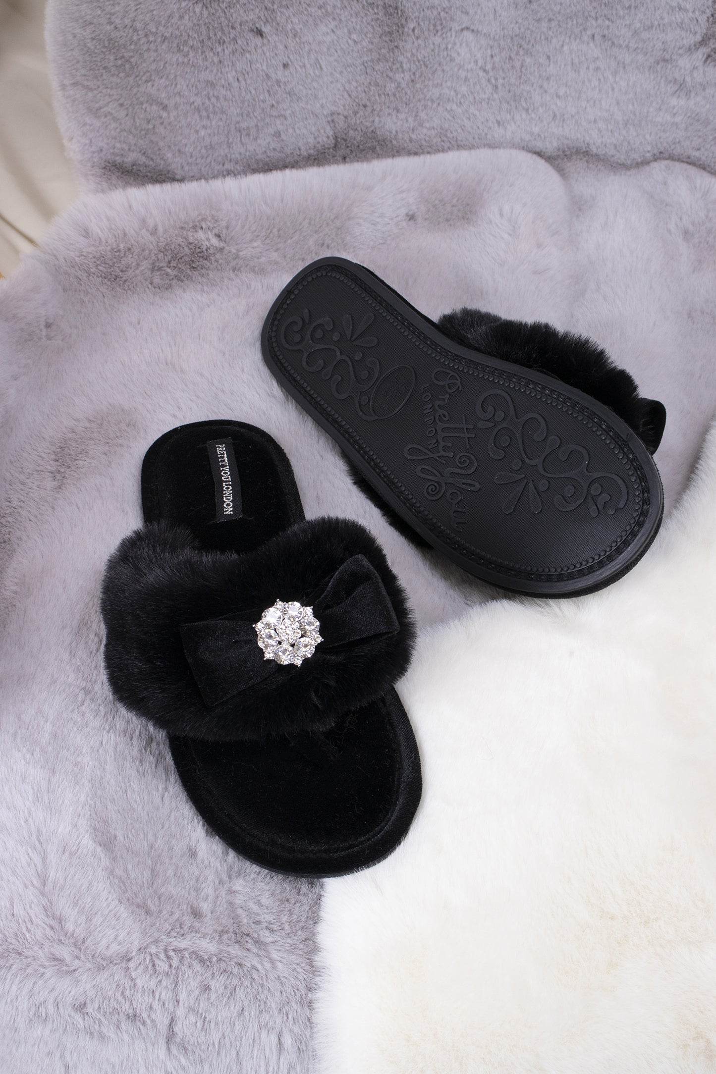 
                  
                    Amelie women's toe post slippers in black with a premium velvet bow and diamante embellishment atop a plush faux fur band from Pretty You London
                  
                